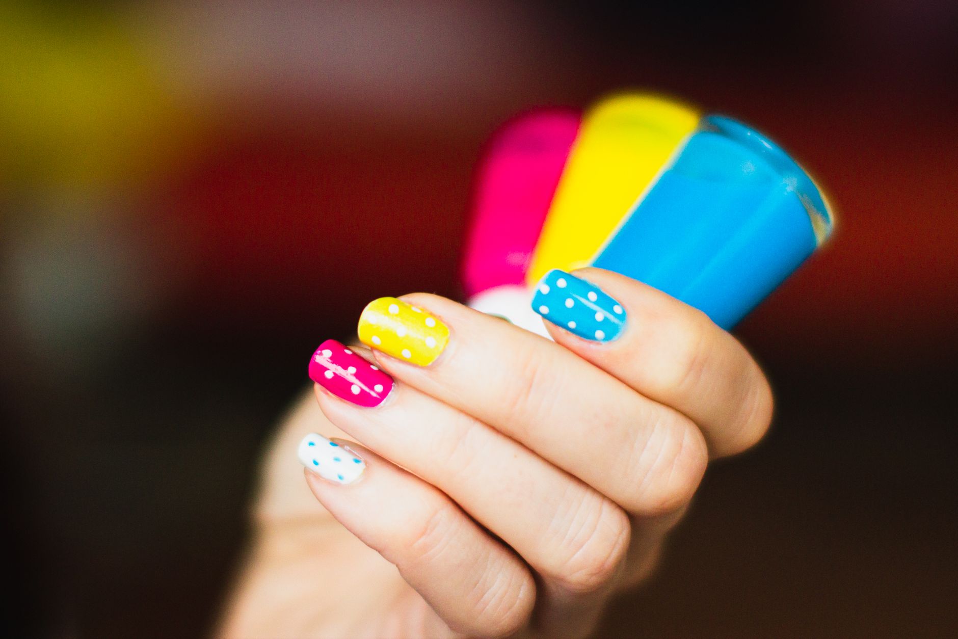 Main aux ongles vernis tenant des flacons de vernis colorés